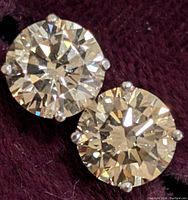 Close-up of two round brilliant diamonds in four-prong settings on dark cloth