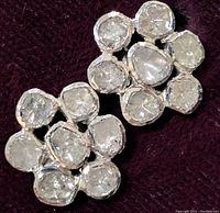 Pair of earrings shown from above on a dark fabric background, displaying the rough diamond chips and stainless steel setting.