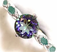 Close-up front view of sterling silver ring featuring a round mystic topaz center stone and pear-shaped emerald stones on the band.