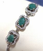Close-up photo showing three emerald stones surrounded by cubic zirconia on a sterling silver bracelet.