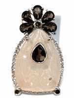 Front view of sterling silver ring showing carved translucent gemstone, clear stones border, and dark brown gemstone flower design.