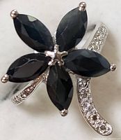 Close-up photos showing flower design ring with marquise sapphire stones and curved band with small clear stones.