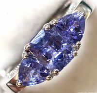Close-up of ring head showing three tanzanite stones with prong settings.