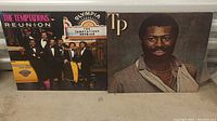 Photo of both record album covers showing The Temptations Reunion and Teddy Pendergrass albums side by side.