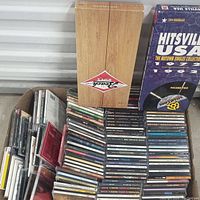 Overview of the CD lot showing stacked jewel cases, Beatles wooden box, and Hitsville USA collection box