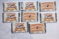 Eight sealed Hershey's trading card packs laid out on a surface showing front of each pack with vintage Hershey's syrup delivery truck and characters illustration.