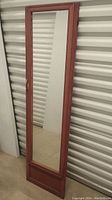 Full view of the tall rectangular mirror with reddish brown wood frame showing overall condition
