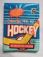 Single sealed pack of 1991-92 O-Pee-Chee NHL hockey cards showing front packaging with blue background, hockey stick, and special insert note.