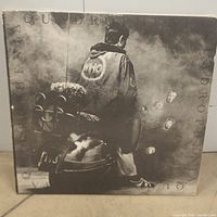 Front cover of The Who Quadrophenia album showing a man in a jacket with The Who logo sitting on a scooter in a smoky environment