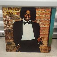 Front cover of Michael Jackson Off The Wall album featuring Michael Jackson in a tuxedo jacket and bow tie in front of a brick wall.