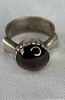 Front view of the vintage sterling silver ring with the dark polished cabochon stone visible on the top and decorative features on the sides.