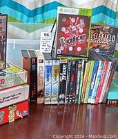 Photo showing Xbox 360 games The Voice and Battlefield Vietnam, several DVD and VHS movies including 'Gods and Generals', and assorted CDs in cases