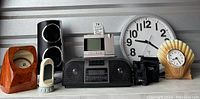 Full view of the lot showing various clocks, electronics, watch winders, binoculars, and radio device arranged on a gray shelf.
