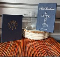 Full view of the crystal cube cross on a faceted base with original blue box labeled 'Noble Excellence Cube Cross' and a new Bible with blue cover and gold religious emblem.