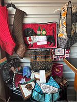 Photo showing a variety of handcrafted pet-themed fabric items including aprons, bags, a quilted appliqué wall hanging or mat, and small pouches arranged in a shelving unit.
