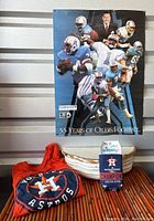Poster showing multiple Houston Oilers football players with a central figure and logo, displayed on a wall with Astros t-shirt and can cooler below.