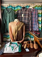 Overall view of lot on rack and table showing shirts, windbreaker, ties, shoes, shoe horns and luggage straps