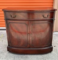 Front view of the mahogany buffet server showcasing the curved design and two cabinet doors with drawer above.