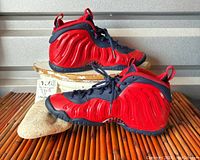 Side view of red and blue Nike youth hi-top sneakers showing waved texture and minor scuffs on toe.