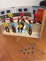 Seven original Star Trek action figures posed on display background with stands, communicators, and phasers arranged in front