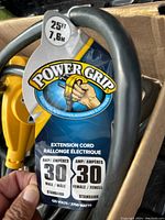 Close-up image showing packaging label with brand name Power Grip, length 25ft, amperage 30 amp male and female, voltage and wattage specifications.