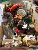 Overview photo of antique bottles, figurines, and clock inside a cardboard box.