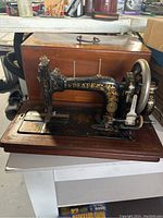 Side view of antique Pfaff sewing machine on wooden base with original wooden box behind it