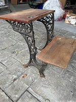 Side view showing ornate cast-iron frame and wooden seat and desktop with wear and patina.