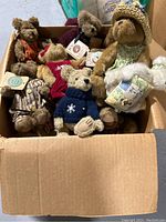 Box filled with Boyd's Bears collectible teddy bear dolls in various outfits and sizes, some with tags attached
