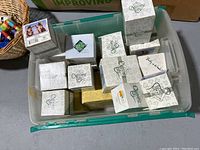 Photo showing multiple figurine boxes inside a plastic bin, including white and patterned boxes with Charming Tails logos and labels.