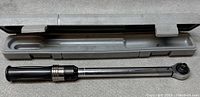 Chrome torque wrench with black handle and adjustable torque dial in plastic case.