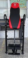Front view of Body Vision inversion table showing padded black and red backrest with logo and handlebars.