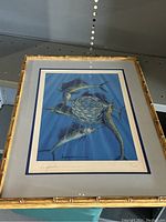 Framed limited edition print with visible signature and number 4/100, bamboo style gold frame.