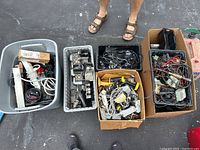 Overview of several bins and boxes containing assorted electronic items and soldering equipment.