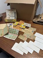 Overview of the lot showing open boxes and envelopes with various stamps and albums laid out on a table.