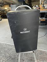 Front view of the black Masterbuilt smoker with logo visible, showing size and exterior condition.