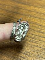 Close-up image showing the dragon head and textured scale details on the sterling silver ring, resting on a wooden surface.