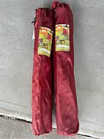 Two red Ozark Trail foldable chair carrying bags stacked on the ground.