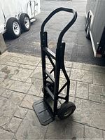 Full view of black metal two-wheel hand truck showing front and handle, tires flat.
