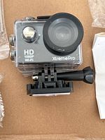 Front close-up image of Xtreme Pro HD 1080P Wi-Fi action camera inside waterproof housing with large lens and button controls visible.