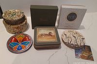 Four sets of coasters including Harrods, Koh Living, Indian, and Japanese sets all arranged for display on a white surface.