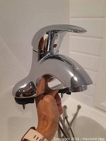 Side angle view of chrome finish American Standard bathroom faucet showing lever and pull rod