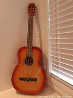 Front view of wooden Croatian tamburica guitar with visible sunburst finish and 3 sets of double strings across the fretboard and bridge.