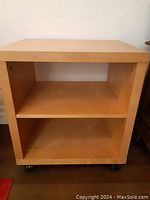 Front view of the solid wood IKEA bedside table showing adjustable shelf and wheels