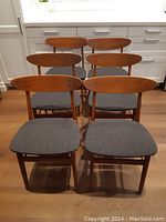 Front view of six teak chairs with gray seats arranged in two rows