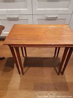 Larger wooden nesting table showing top surface with visible scratches and watermarks.