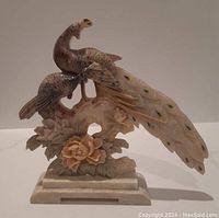 Front angle showing two peacocks perched on a floral base with detailed carving and colored feather accents.