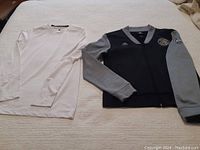 Photo showing both Adidas Raptors jacket and white Starter long sleeve top laid flat.