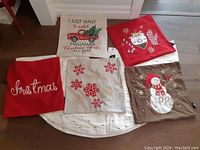 Five Christmas-themed throw pillow covers displayed flat on the floor with various holiday designs.