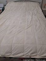 Weighted blanket spread out on a bed showing its texture and stitched vertical panel pattern.